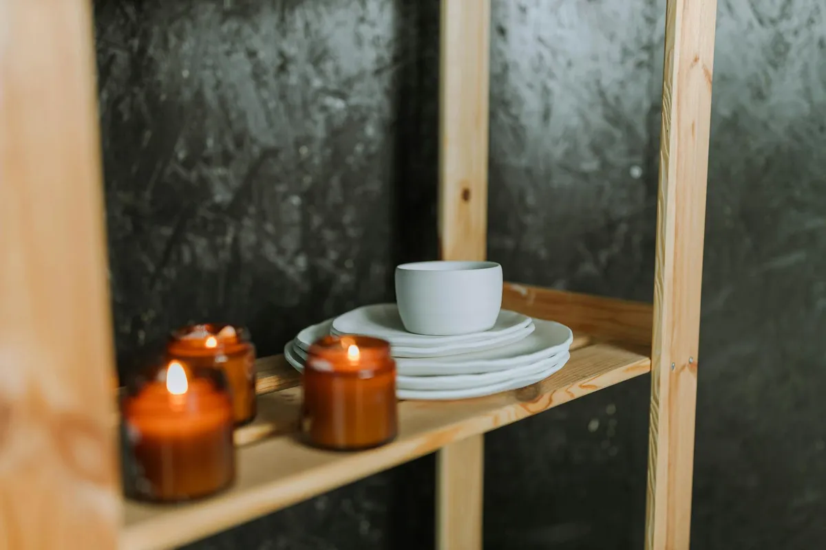 A small set of handmade plates and a knife on a wooden shelf