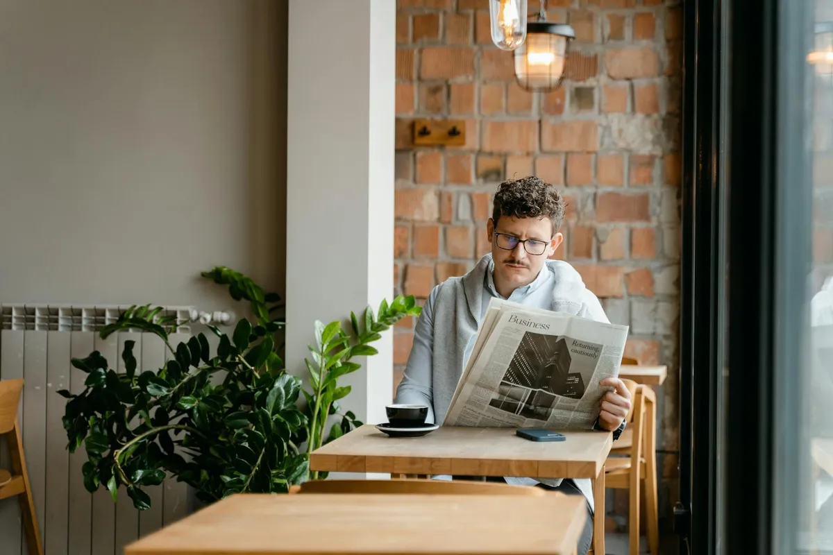 A solo traveler at a small cafe table with a newspaper